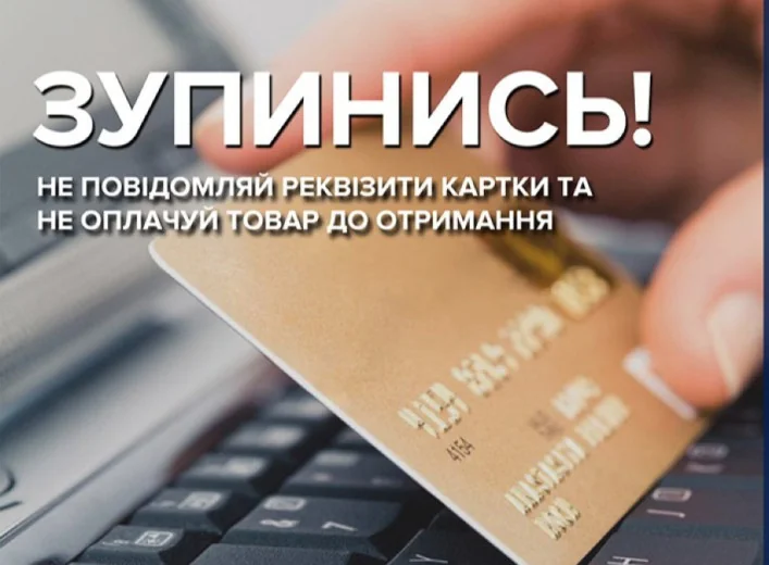 Рука тримає золоту банківську картку над клавіатурою ноутбука з попередженням