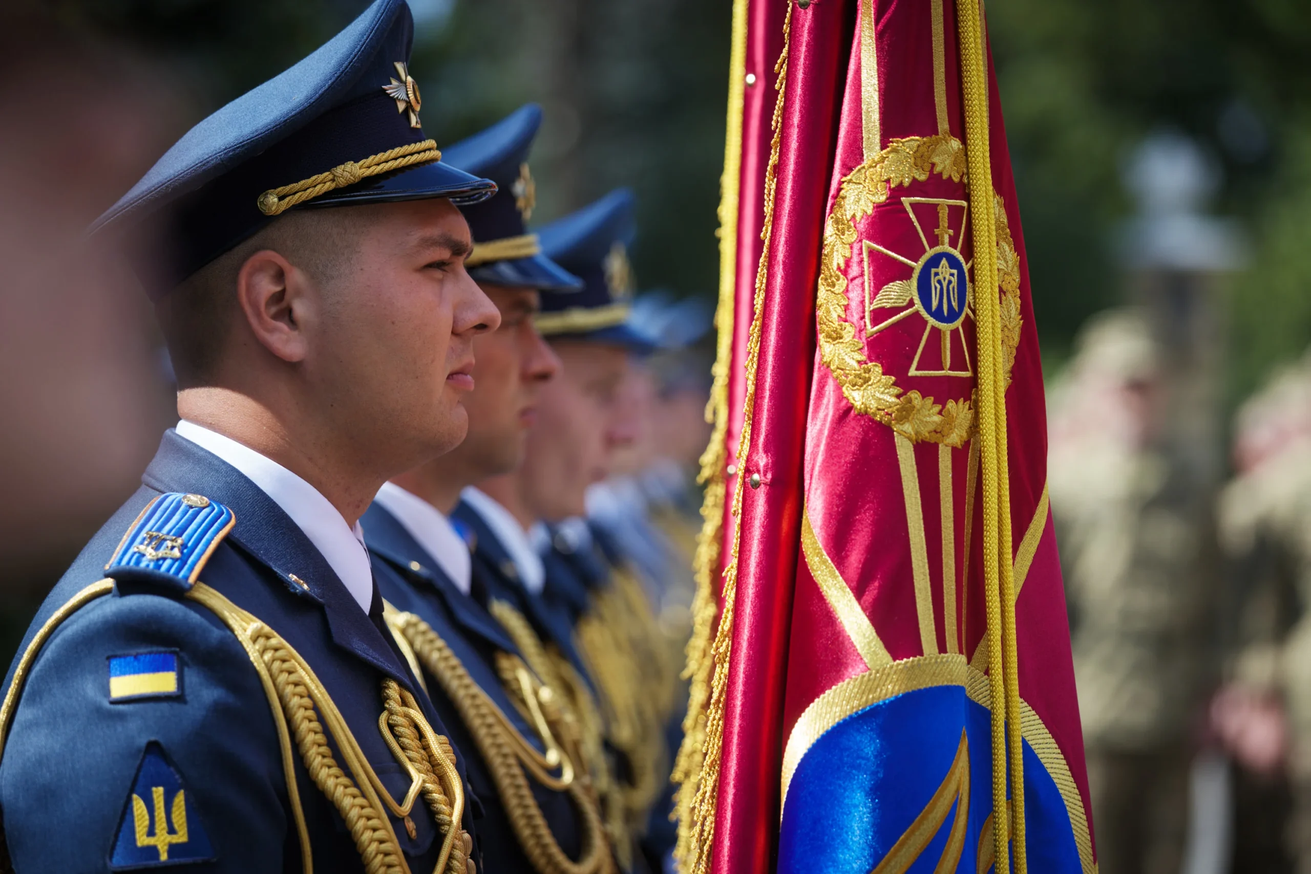 Українські офіцери в парадній формі стоять біля прапора з тризубом