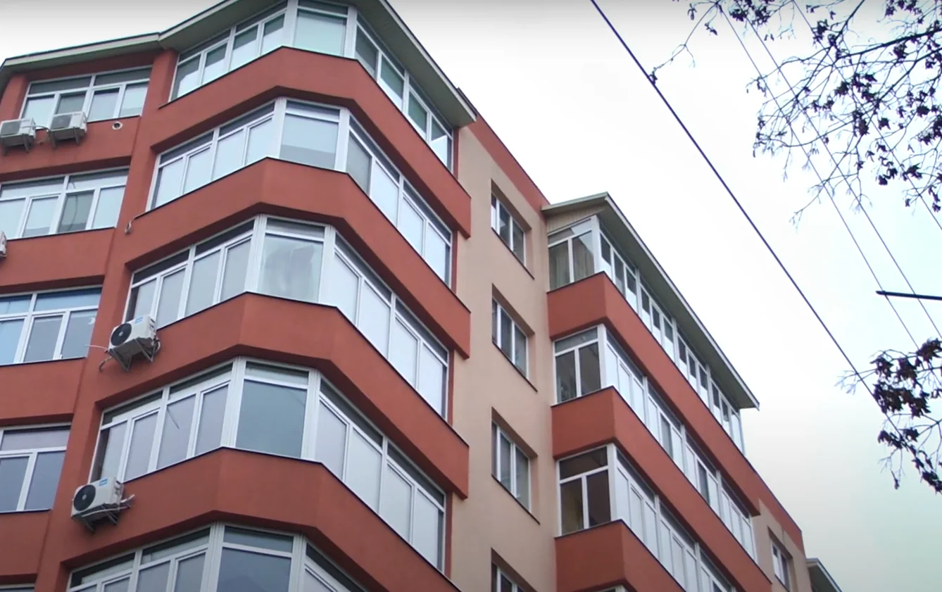 Багатоповерхівка з теракотовим фасадом, еркерами та кондиціонерами під сірим небом