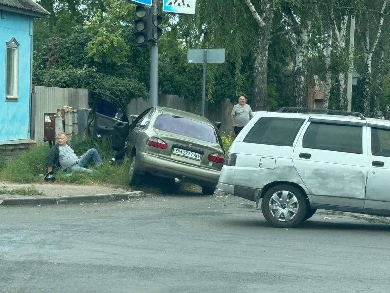 Зіткнення двох авто на перехресті, чоловік сидить на траві в Сумах