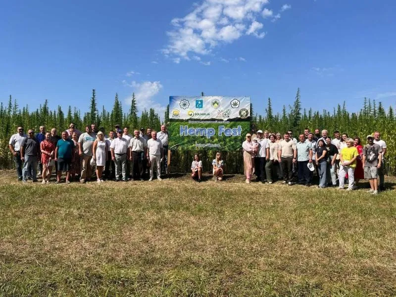 Учасники Hemp Fest стоять біля банера на тлі поля конопель