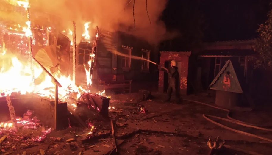Рятувальник гасить полумя деревяного будинку вночі після удару