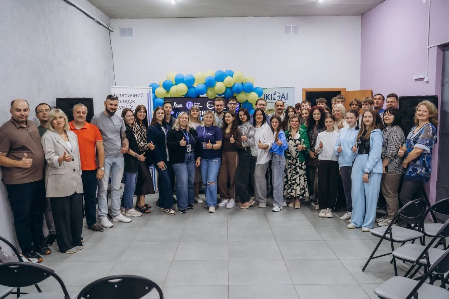Група людей позує в залі з синьо-жовтими кульками та банерами