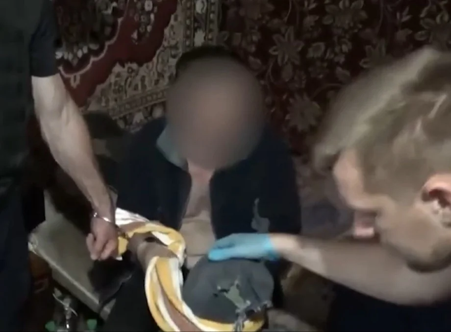 Затриманий із розмитим обличчям і поліцейський у рукавичці оглядають речі