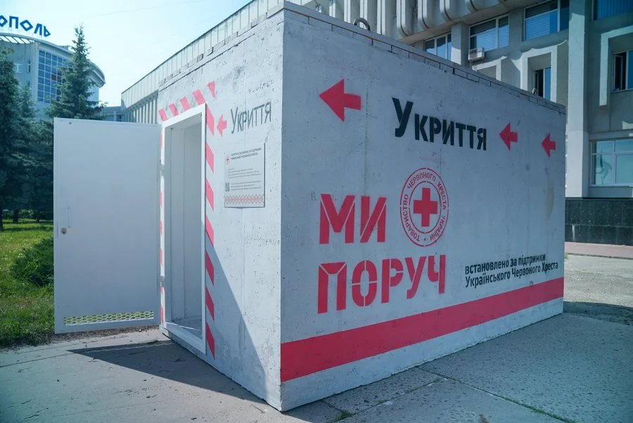 Бетонне мобільне укриття з написом «Ми поруч» і логотипом Червоного Хреста біля будівлі