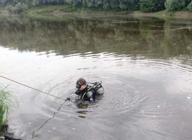 Водолаз ДСНС у спорядженні занурюється у річку, тримаючи страхувальний трос